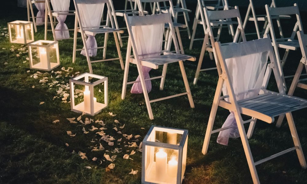 pillar candles in lanterns down the center aisle of a wedding