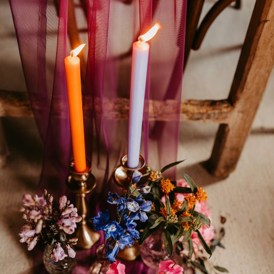 two taper candles of different colors with vibrant flowers