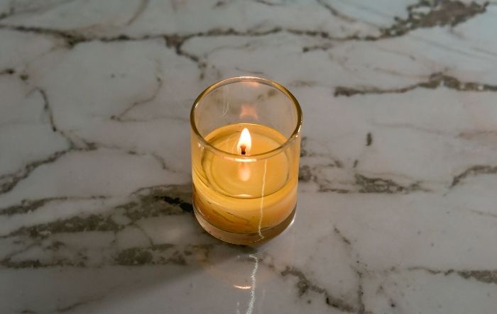 Lit votive candle in a narrow holder