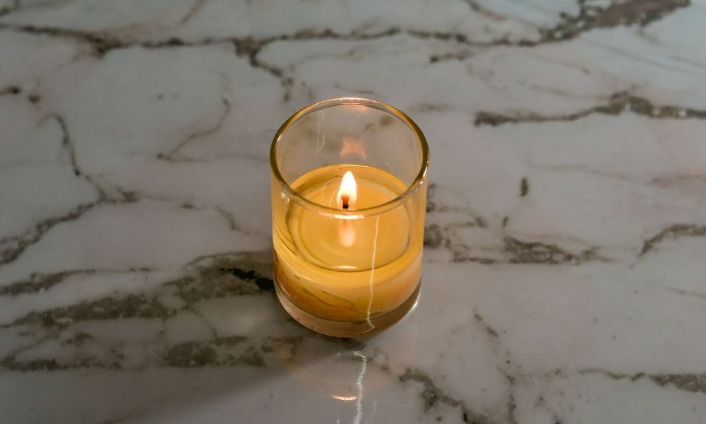 Lit votive candle in a narrow holder