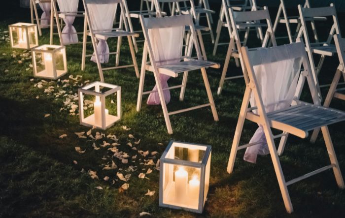 pillar candles in lanterns down the center aisle of a wedding