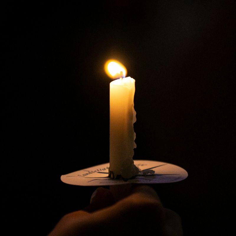 person holding a taper candle with a bobeches